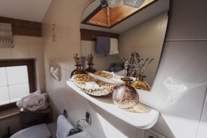 A bathroom with a shelf holding decorative items, a mirror, and a window. - Apartment 'Töllhof Studio - Bauernstube' with Mountain View and Wi-Fi (Rasa)