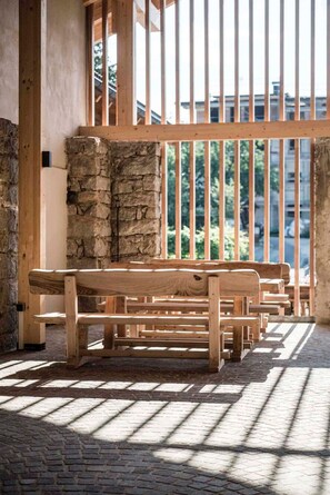 A wooden bench area with a stone wall and a view of greenery through a railing. - Apartment 'Töllhof Studio - Bauernstube' with Mountain View and Wi-Fi (Rasa)