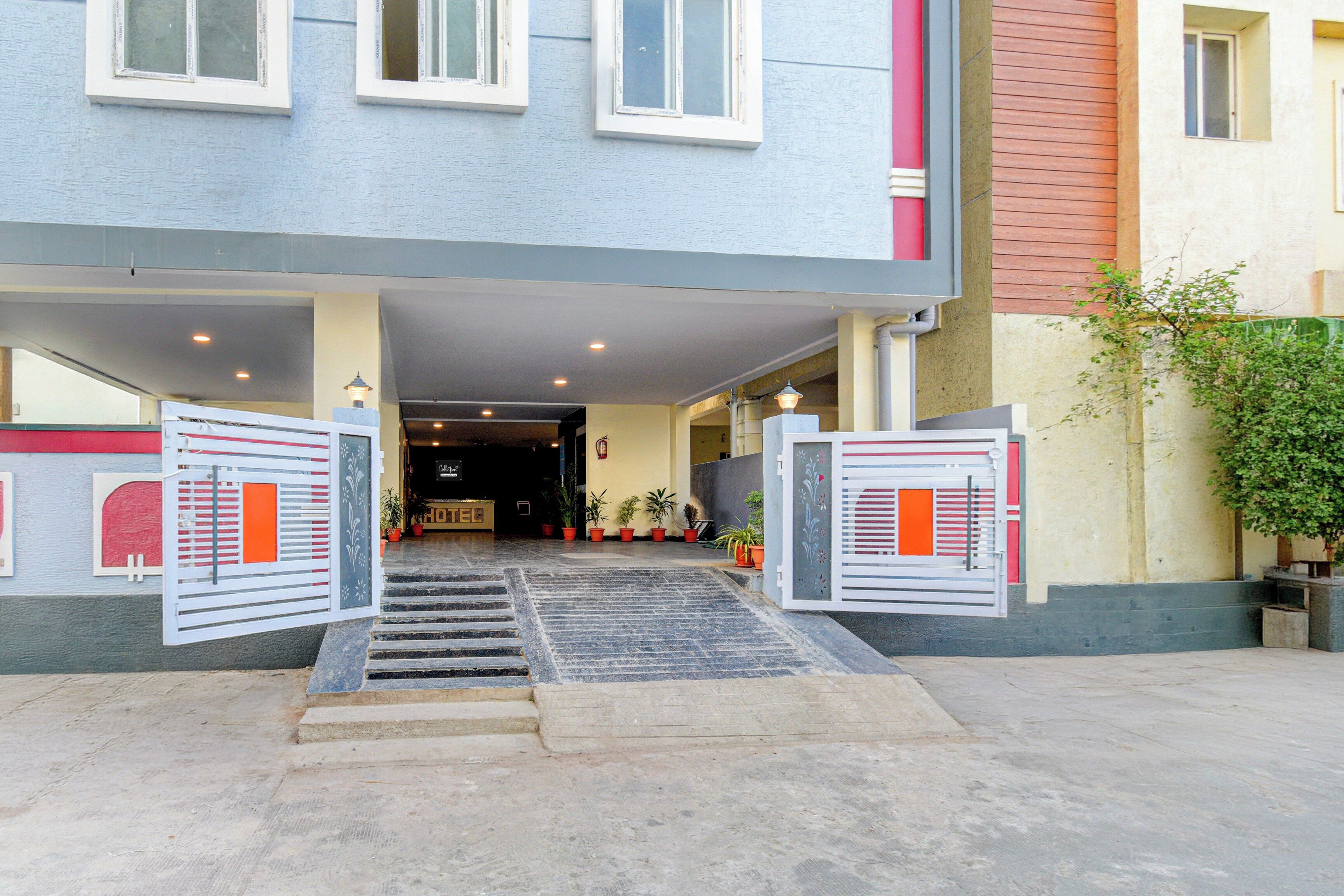 Entrada de un hotel con un vestíbulo techado, escalones y plantas en macetas.