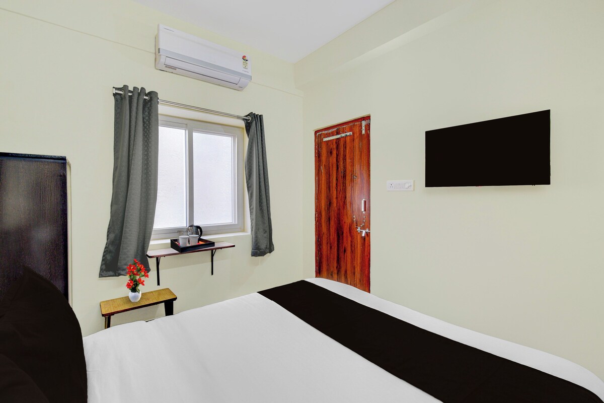 Habitación de hotel con cama, ventana con cortinas, televisor montado en la pared y equipo de aire acondicionado.