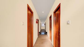 Un pasillo con puertas de madera, un extintor y un interruptor de luz en la pared.