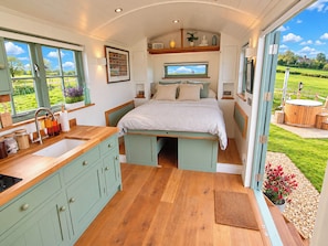 A compact bedroom with a bed, a TV, and a view of the outdoors. - Oak Hut (Bishops Castle)