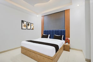 Habitació d'hotel moderna amb un llit gran, una tauleta de nit, un vas de flors i tres quadres enmarcats a la paret.