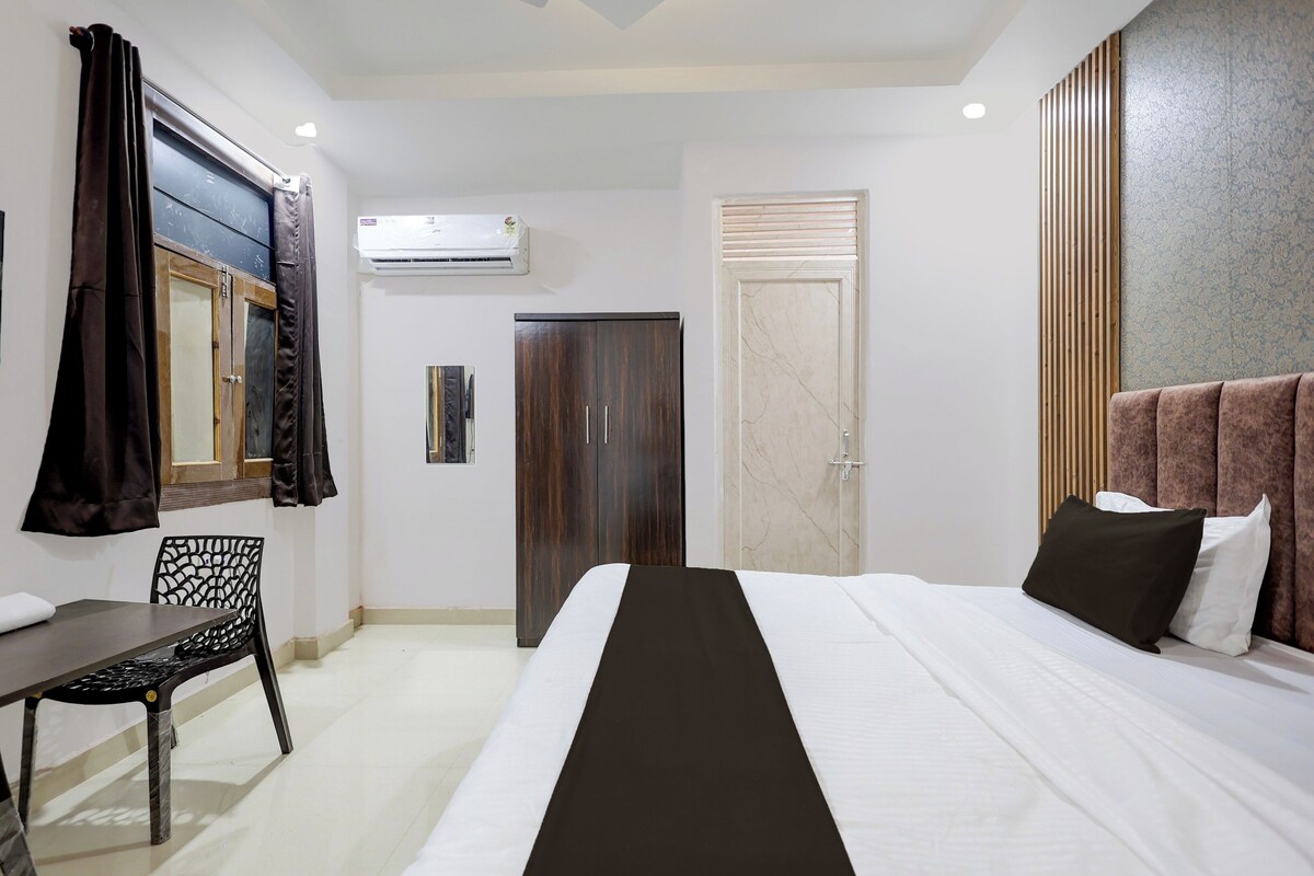 Habitació d'hotel amb llit, escriptori, cadira, armari i aire condicionat.