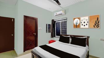 A bedroom with a bed, a ceiling fan, an air conditioner, a window with curtains, and wall art.