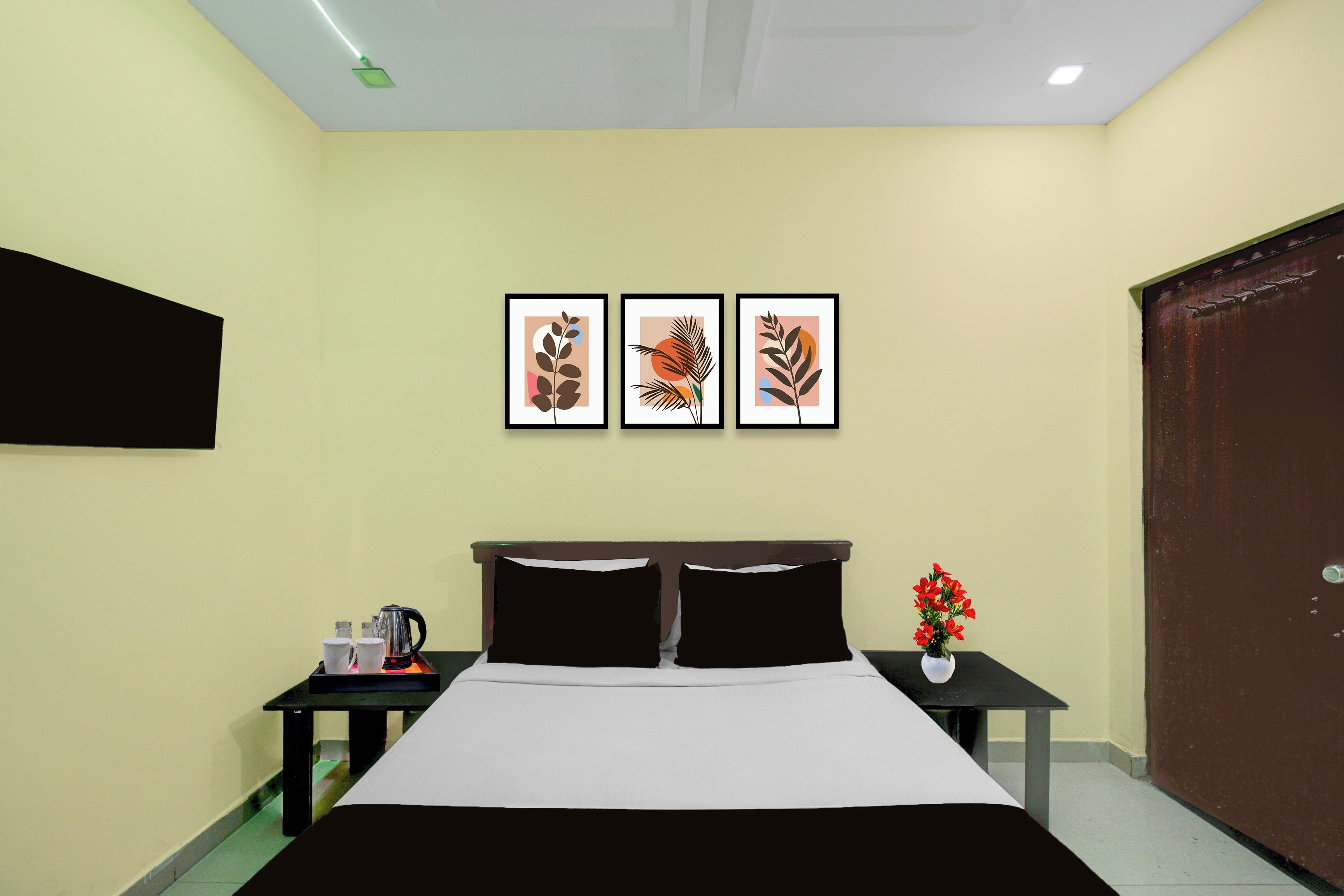 Une chambre d’hôtel avec un lit, une table de chevet sur laquelle se trouve une machine à café, et trois œuvres d’art encadrées accrochées au mur.