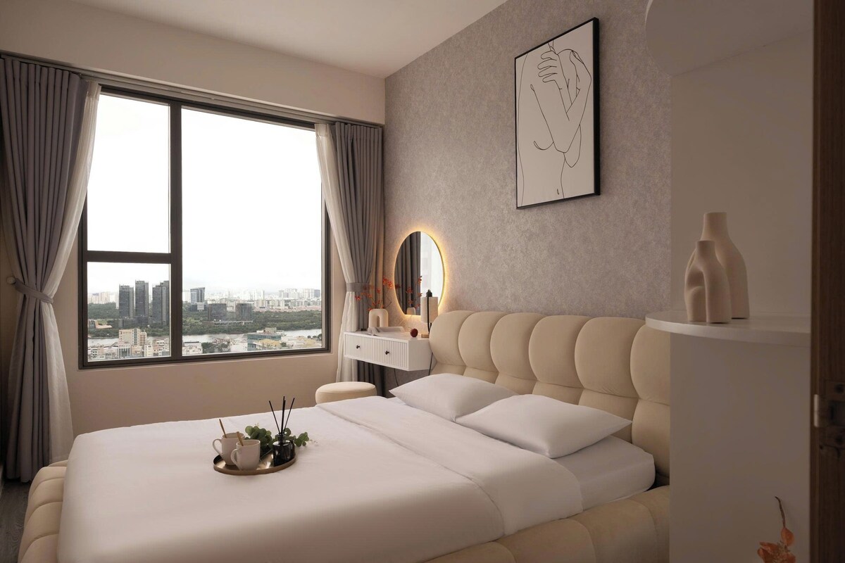 A modern hotel room with a large bed, a bedside table, a mirror, and a city view.