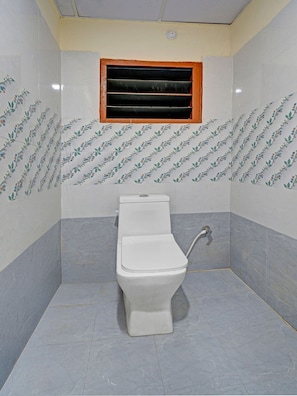 Un baño pequeño con inodoro, ventana y paredes de azulejos.