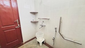 A small bathroom with a toilet, a shower, and a red door. - Tranquil Retreat (Chikkamagaluru)