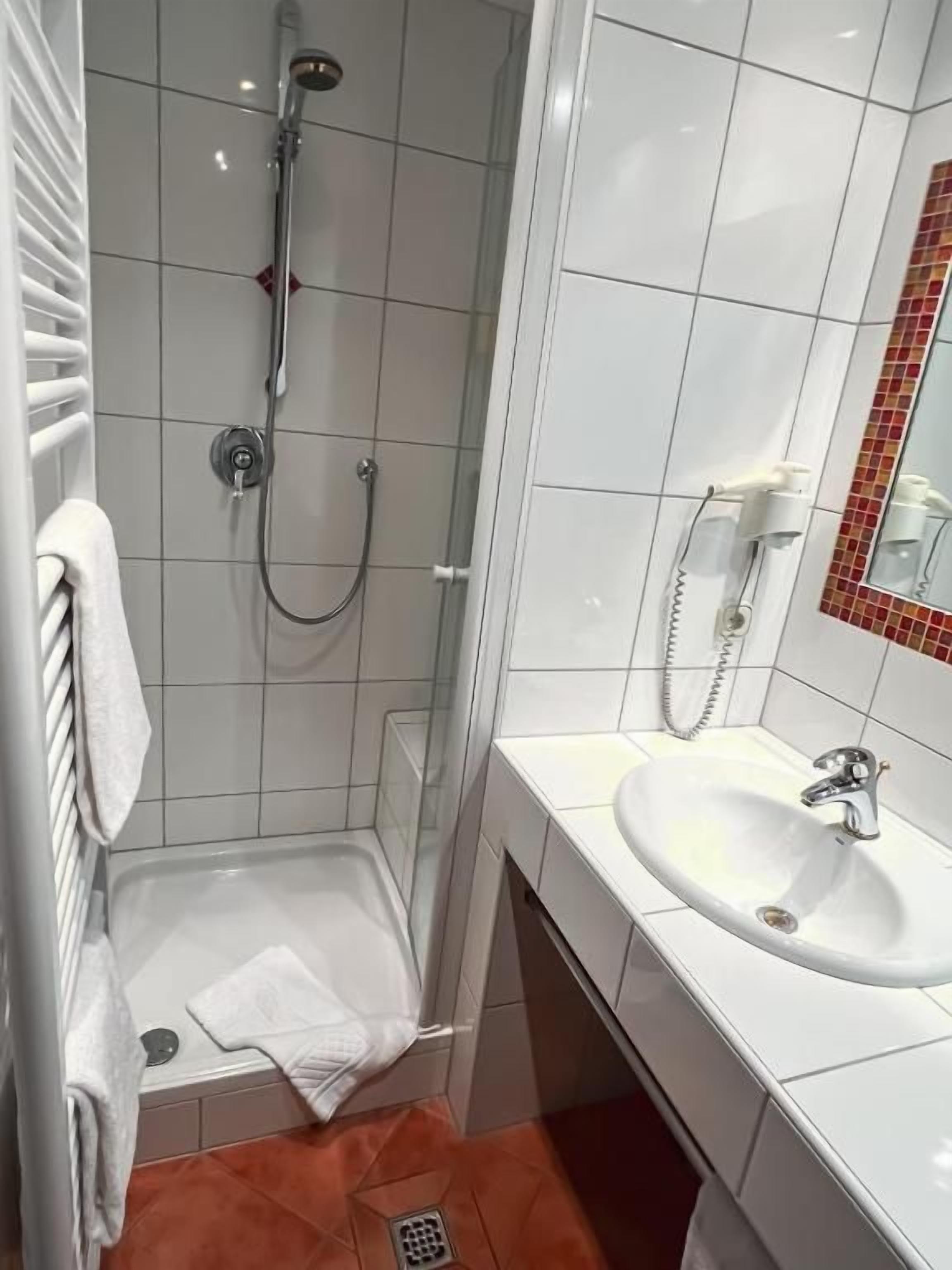 Un baño con ducha, lavamanos y espejo.