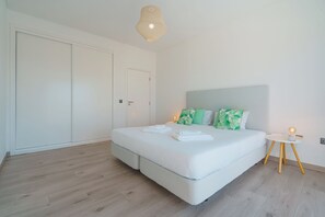 A modern bedroom with a large bed, a small bedside table, and a hanging light fixture. - Silver Villa with private pool and sea view (Atalaia)