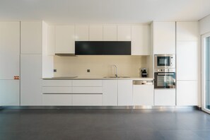 A modern kitchen with white cabinets, a stainless steel range hood, a sink, and a built-in oven. - Silver Villa with private pool and sea view (Atalaia)