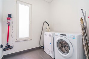 A laundry room with a washing machine, a vacuum cleaner, and a window. - Silver Villa with private pool and sea view (Atalaia)