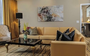 Una sala de estar con sofá, sillón, mesa de centro y un cuadro en la pared.