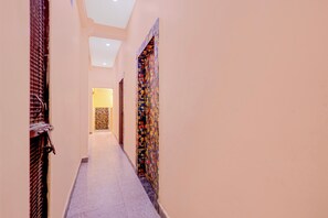 A corridor with a tiled floor, a patterned wall, and a door at the end. - Super Hotel O Sant Ravidas Ghat Varanasi (Varanasi)