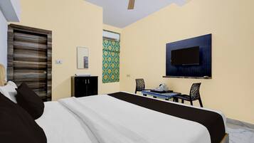 A hotel room with a bed, a desk, a television, and a ceiling fan.