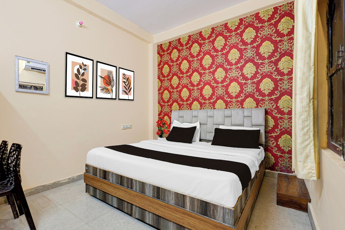 A bedroom with a bed, a headboard, a wall-mounted air conditioner, and three framed artworks.