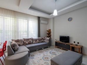Una sala de estar moderna con un sofá, una televisión y un comedor con sillas rojas.