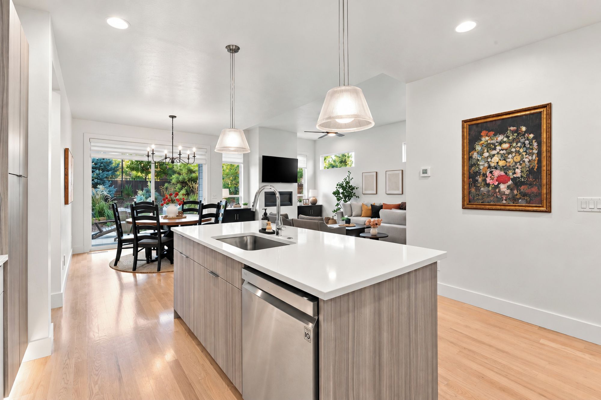 Cocina moderna con isla central, iluminación colgante y zona de comedor con vistas al jardín.
