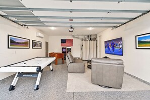 Ein Freizeitraum mit Kicker, Billardtisch, einer Couch und einem Fernseher.