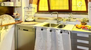 A kitchen with a sink, a dish rack, and a window with curtains. - La Cicala - Charm & Relaxation Just 5 Minutes from the Sea (Rosignano Marittimo)