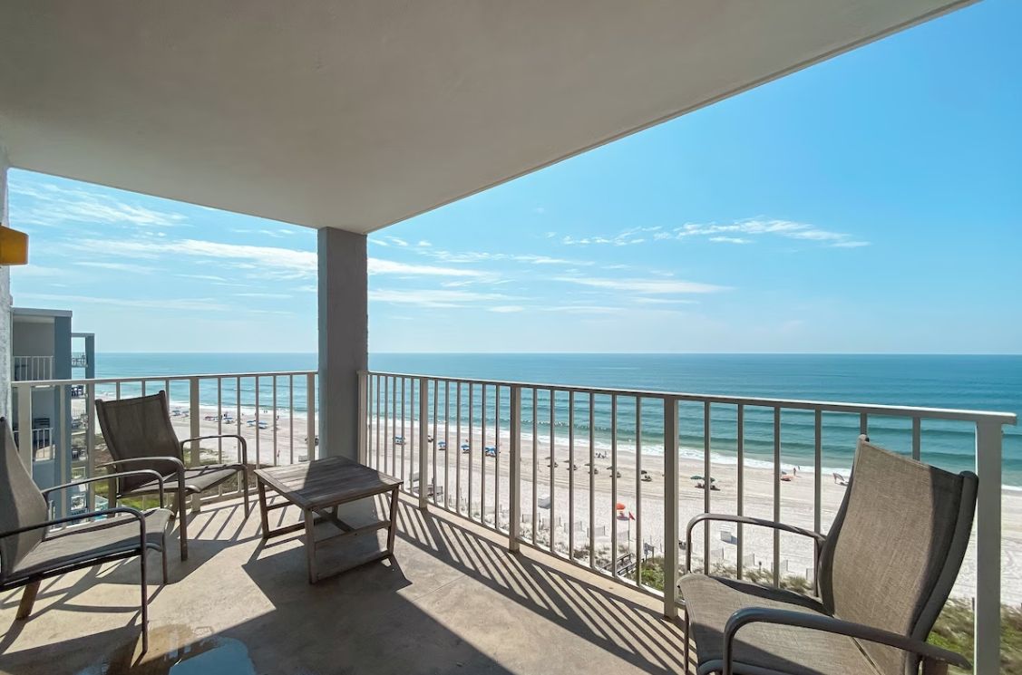 A balcony with a view of the beach and ocean.