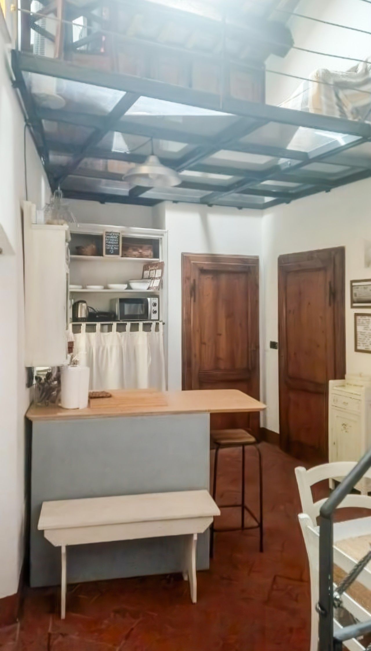 Una cocina compacta con una mesa de madera, una banca y un microondas.