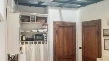 Una cocina compacta con una mesa de madera, una banca y un microondas.