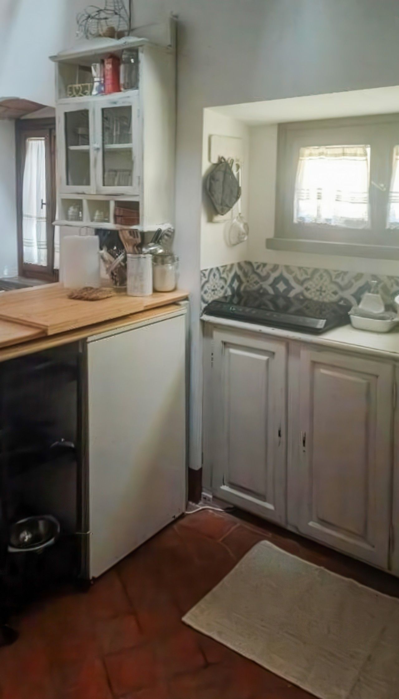Cocina con armarios blancos, encimera de madera y salpicadero de azulejos.