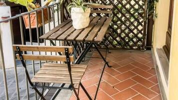 A wooden table and bench set on a tiled patio with a lattice fence in the background.