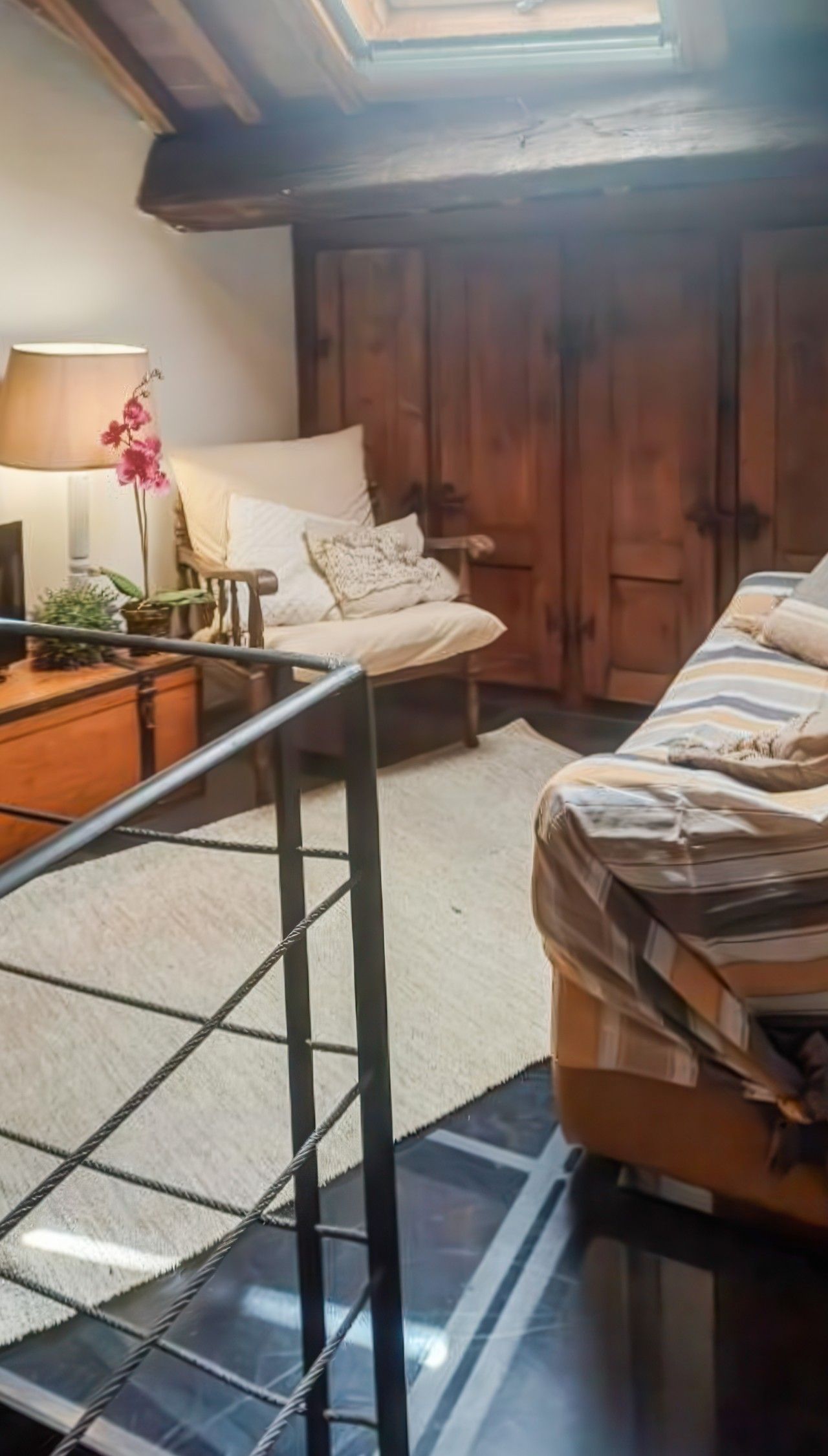Un dormitorio con cama, mesita de noche, lámpara y ventana con vistas al exterior.