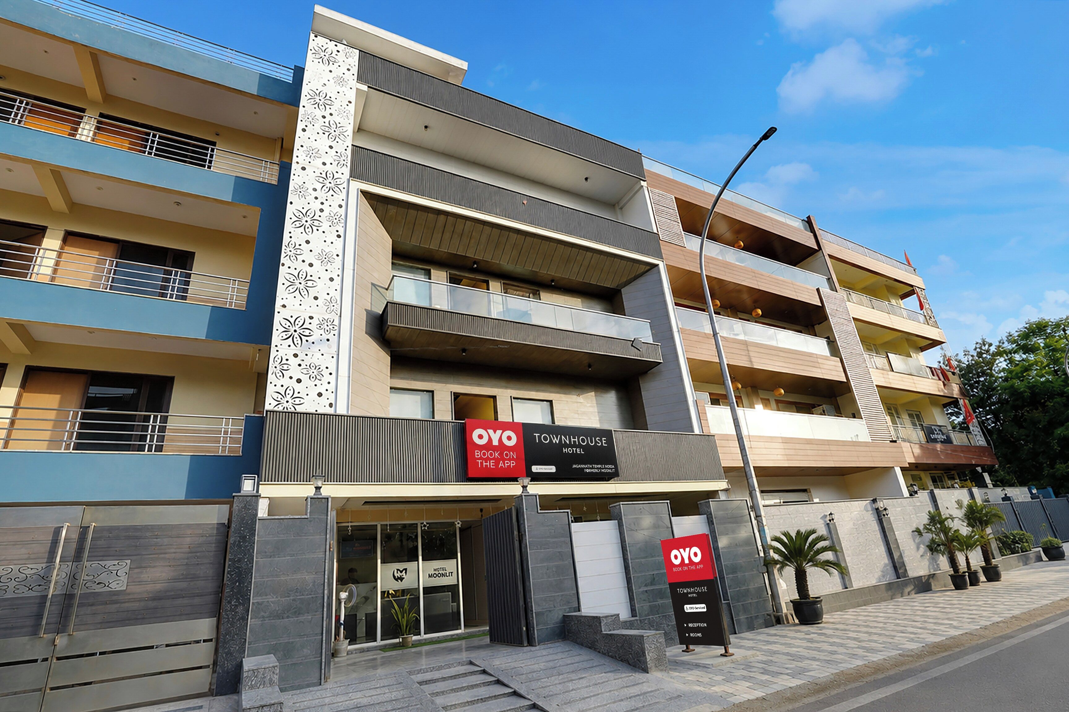 A multi-story hotel with balconies, a modern facade, and signage for booking on the app.