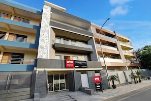 A multi-story hotel with balconies, a modern facade, and signage for booking on the app. - Townhouse Jagannath Temple Noida (Noida)