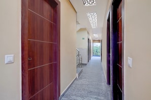 A hotel corridor with wooden doors, a staircase, and a view of the outdoors. - Townhouse Jagannath Temple Noida (Noida)