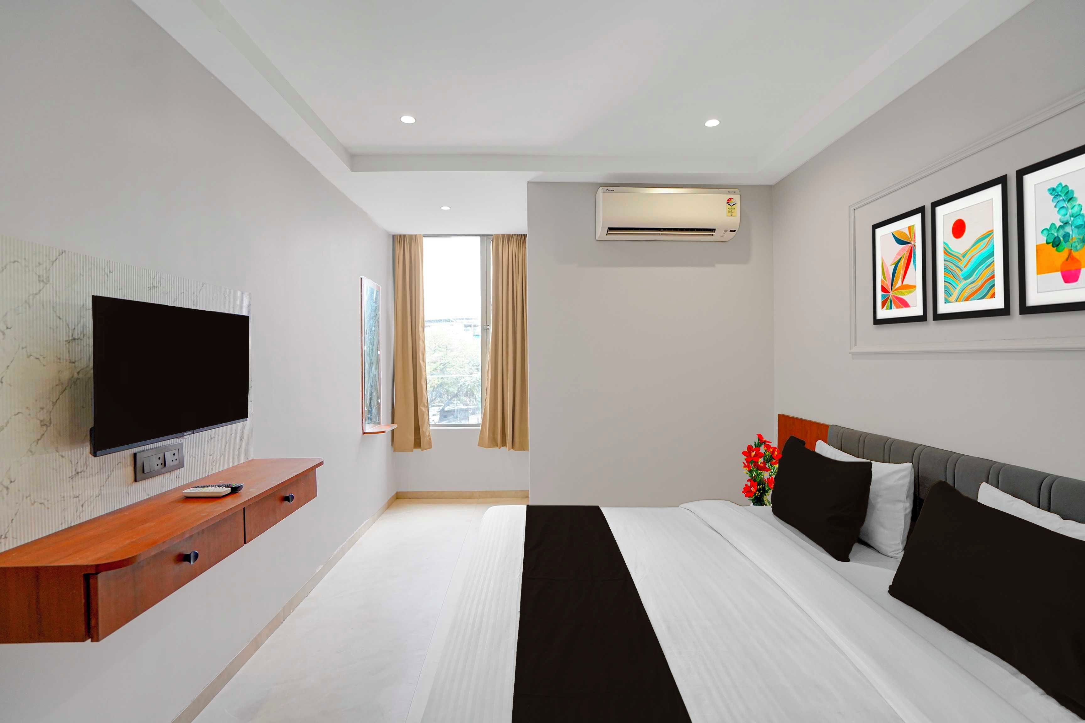 Habitación de hotel moderna con televisión de pantalla plana, cama con ropa de cama blanco y negro, mesita de noche de madera y aire acondicionado instalado en la pared.