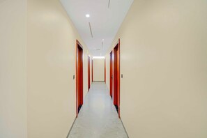 Un pasillo largo y estrecho con puertas a ambos lados y un suelo de color claro.