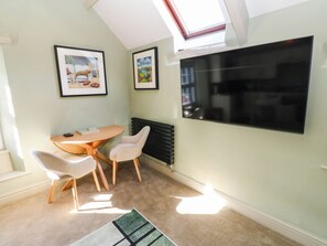 A room with a skylight, a large flat-screen TV, a table with chairs, and framed pictures on the wall. - Sands Green (Appleby-in-Westmorland)