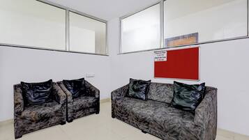 Un área de espera con dos sofás, un letrero rojo y ventanas amplias.