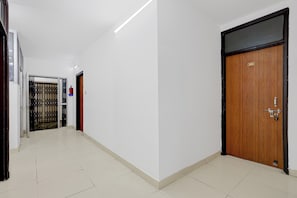 Un pasillo con una puerta de madera identificada con el número 202 y una reja de metal.