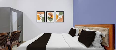 A modern bedroom with a bed, a wooden headboard, a desk, and a chair. There are three framed artworks on the wall.