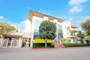 Un edificio moderno con un gran muro de cristal, un árbol en frente y una entrada protegida por un portón.