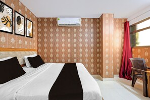 A hotel room with a bed, a chair, a window with curtains, and an air conditioning unit. - Super Hotel O Vineet Khand Gomti Nagar (Lucknow)