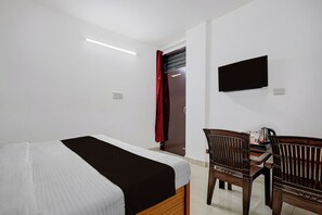 Una habitación de hotel con una cama, un escritorio con una silla, un televisor y una cortina roja.