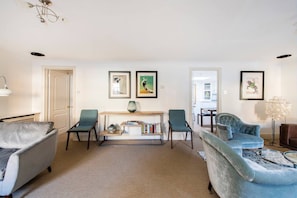 A living room with a sofa, two armchairs, a coffee table, a console table with books and a vase, and framed artwork on the wall. - 2 Bed Apartment, Notting Hill (London)