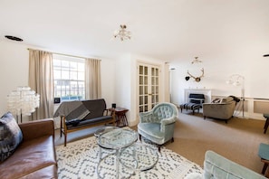 A living room with a sofa, armchairs, a coffee table, and a fireplace. - 2 Bed Apartment, Notting Hill (London)