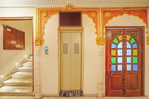 Een trap die leidt naar een kamer met een traditionele deur en een lift.
