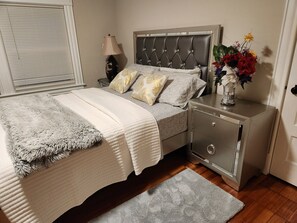 A neatly arranged bedroom with a bed, bedside table, lamp, and a small cabinet. - Blue siren nest (Ludlow)