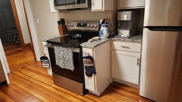 A kitchen with a stove, microwave, coffee maker, and refrigerator.