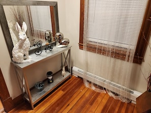 A room with a wooden floor, a white decorative rabbit sculpture, a bicycle, and a mirror on a console table. - Blue siren nest (Ludlow)