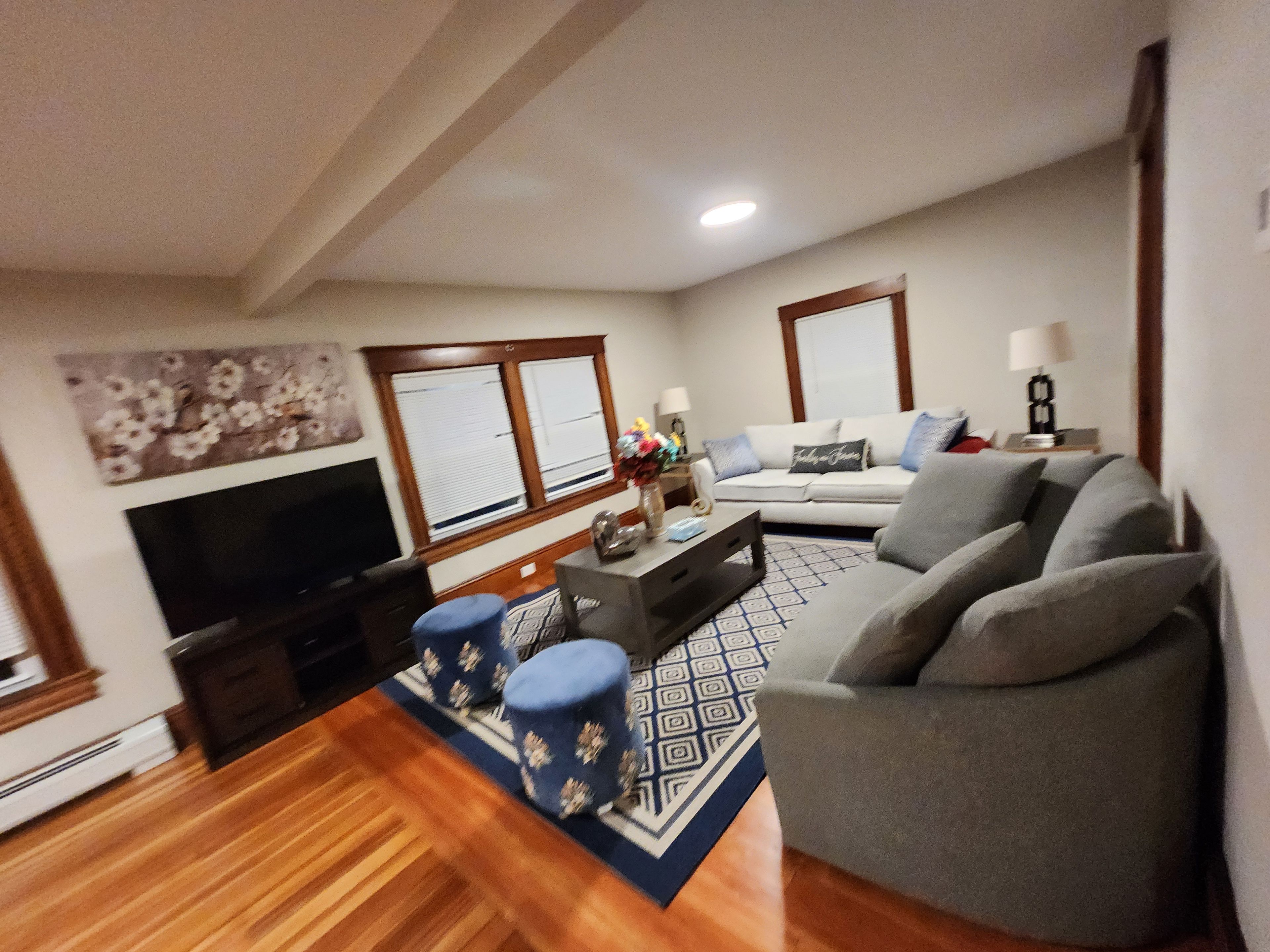 A living room with a sofa, a coffee table, a TV, and a patterned rug.